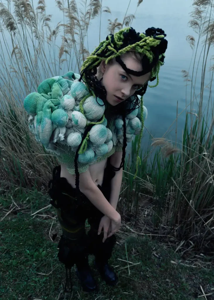 modella vestita con abiti upcycling scattata in una location con un fiume alle spalle
