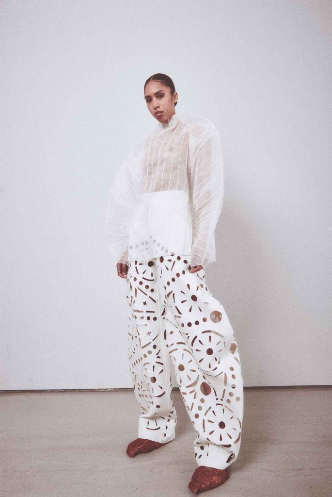 modello su un set con indosso un completo bianco