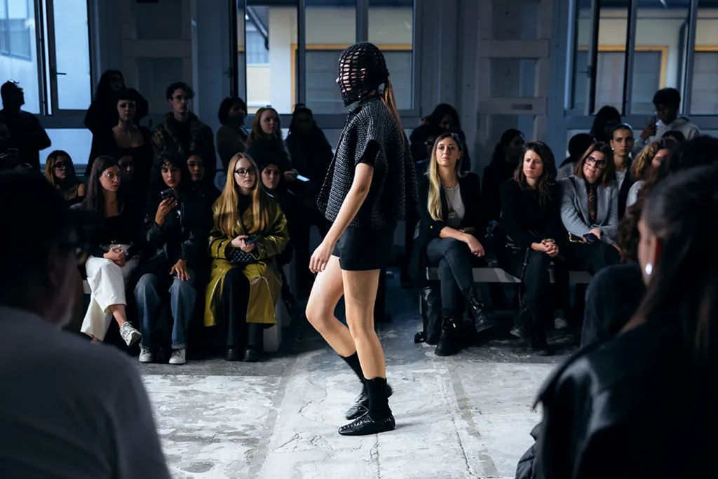 Modella con vestito nero sfila in passerella alla sfilata di Ferrari Fashion School.