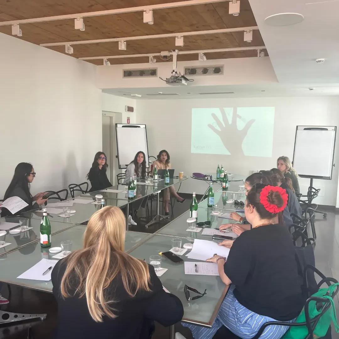 un gruppo di studentesse del Master sedute intorno al tavolo con una presentazione all'azienda di profumi