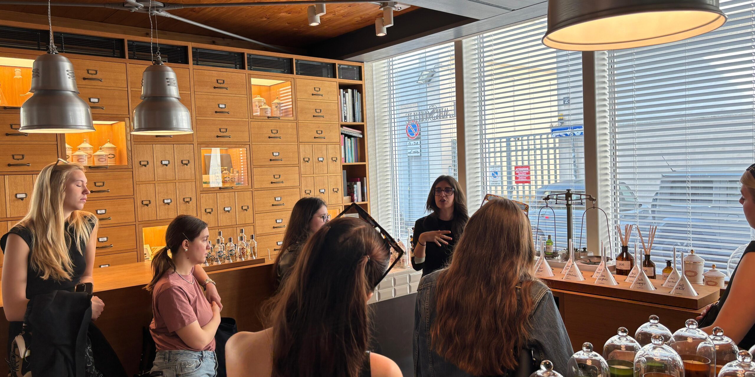 un gruppo di studentesse del Master all'interno di un locale con profumi che ascoltano una lezione