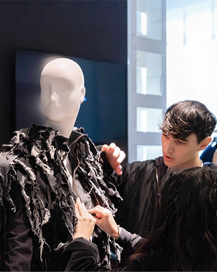 Students fix the jacket on a mannequin.